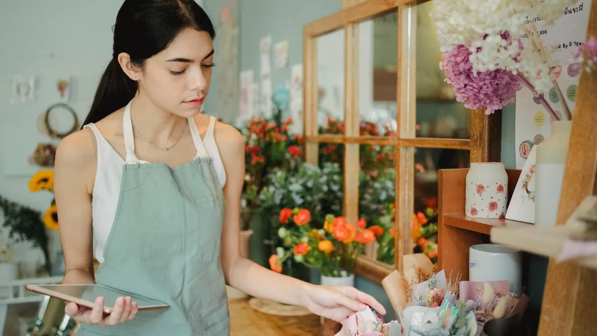 Florist managing online flower orders on a tablet in her shop